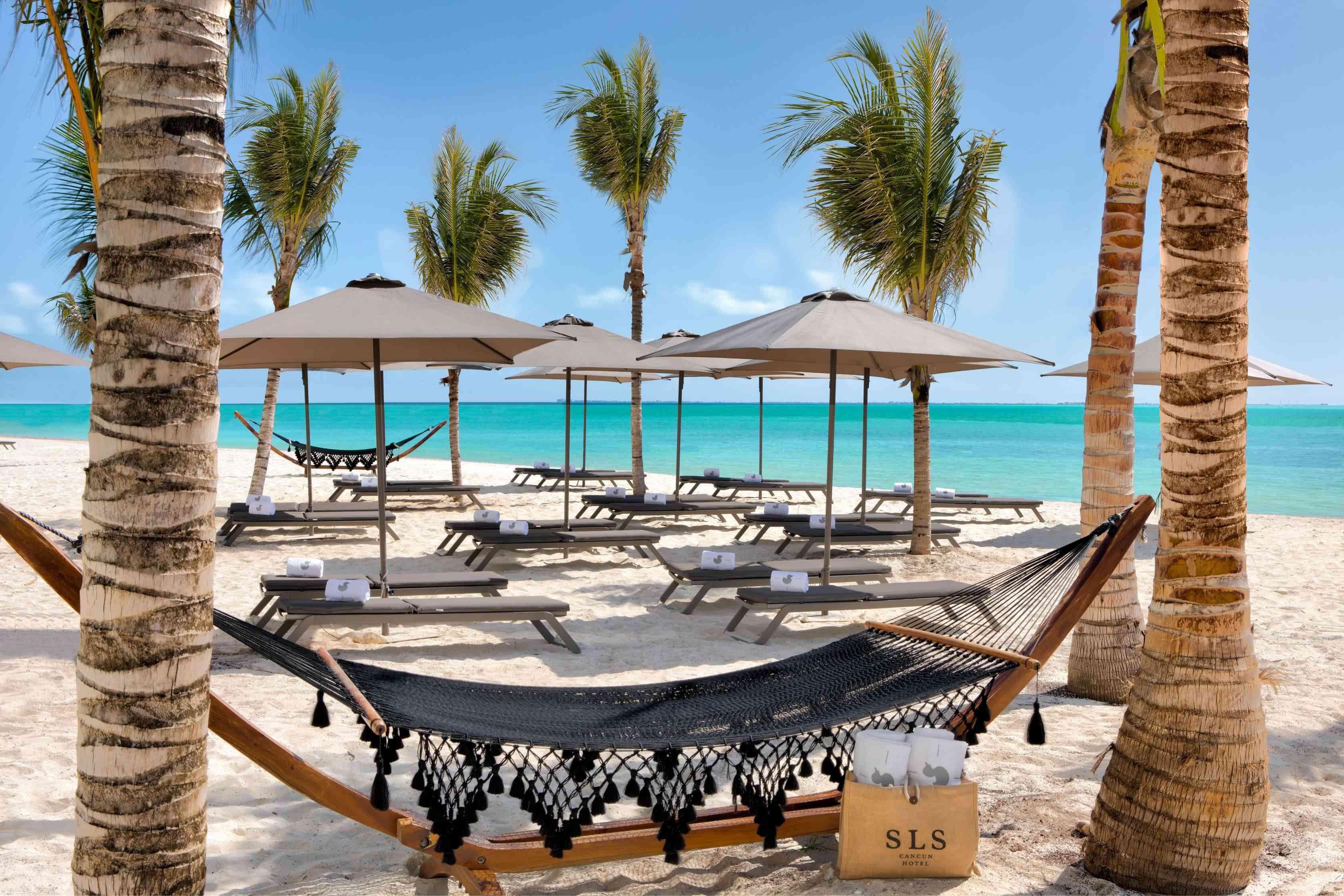 منطقة جلوس على الشاطئ بها أراجيح شبكية وكراسي استلقاء مغطاة بالمظلات